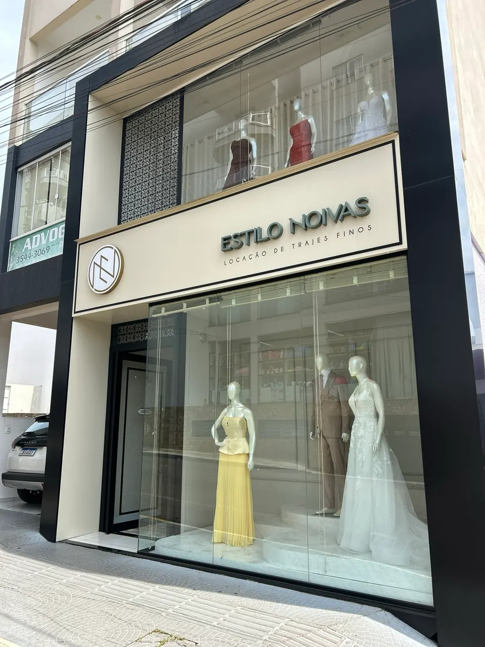 Fachada da loja Estilo Noivas, com vitrine de vestido de noiva, terno e vestido amarelo
