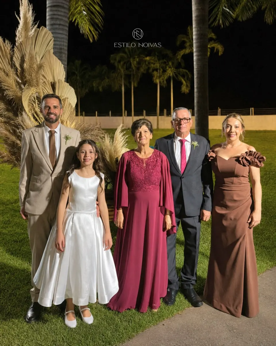 Família em casamento ao ar livre: homens de terno, daminha de branco e mulheres de vestido longo