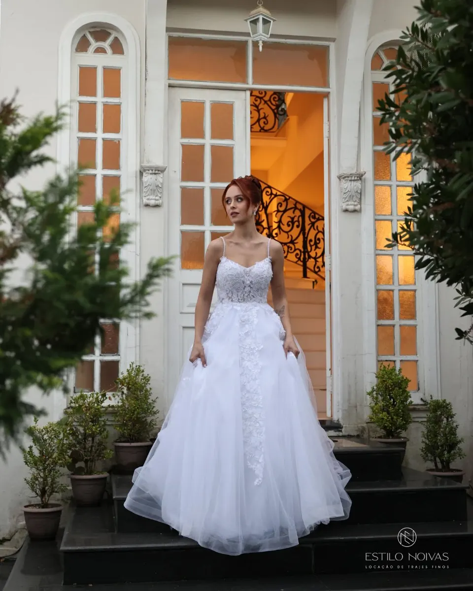 Noiva com vestido de saia volumosa na escadaria de uma casa clássica