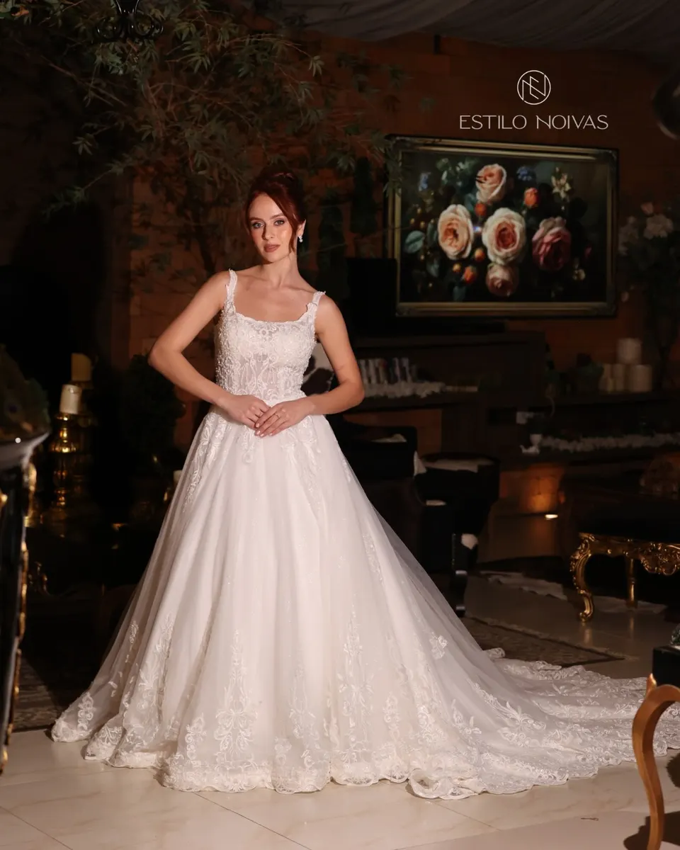 Noiva com vestido de alças e cauda longa em salão decorado