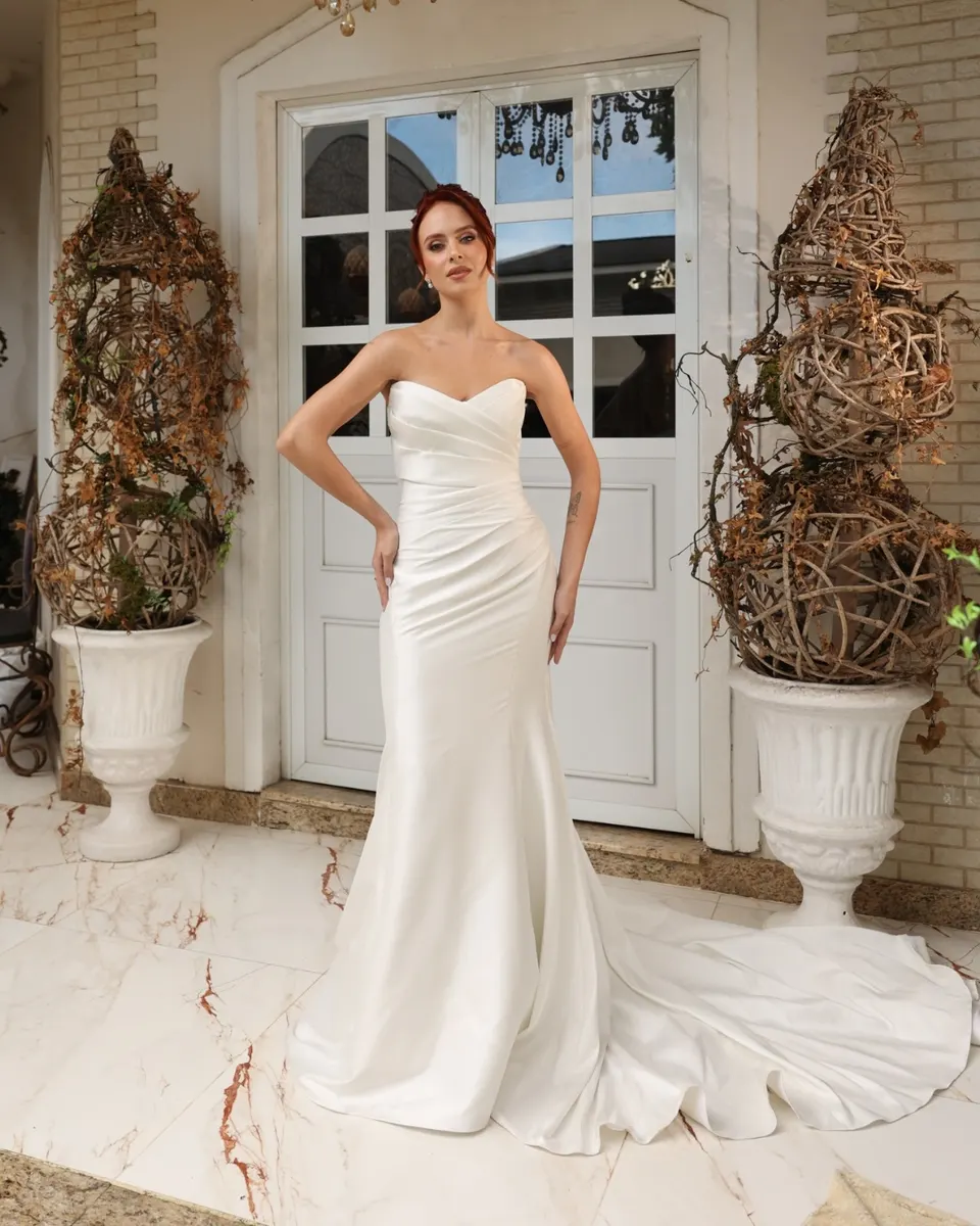Noiva com vestido sereia de cetim diante de porta branca